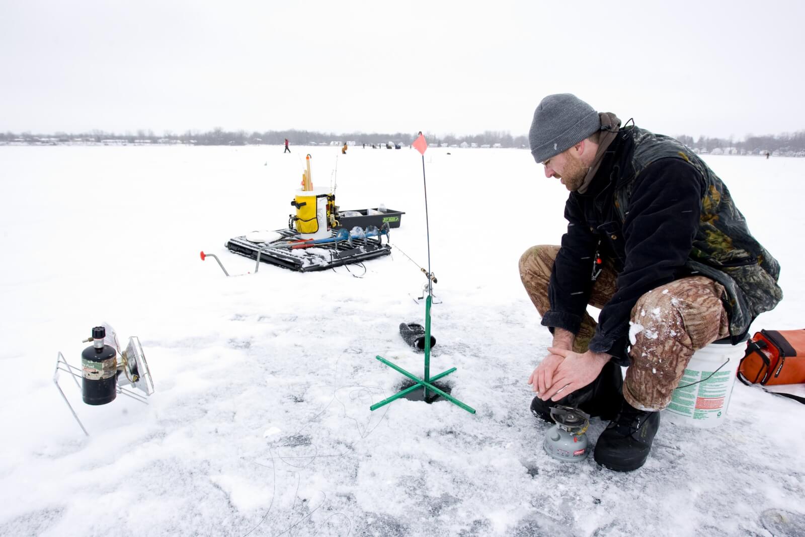 Northern Pike Fishing in Cayuga County Excels in Winter Man ice fishing on frozen lake