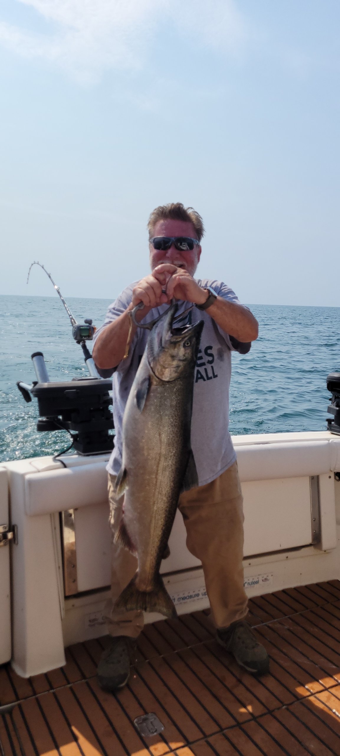 man who was fishing on a charter boat holding up a king salmon he just caught