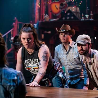 2025 Live Theatre Is Magical: Why I Believe in the Power of the Stage women wearing a black t shirt with her hand on a bar.