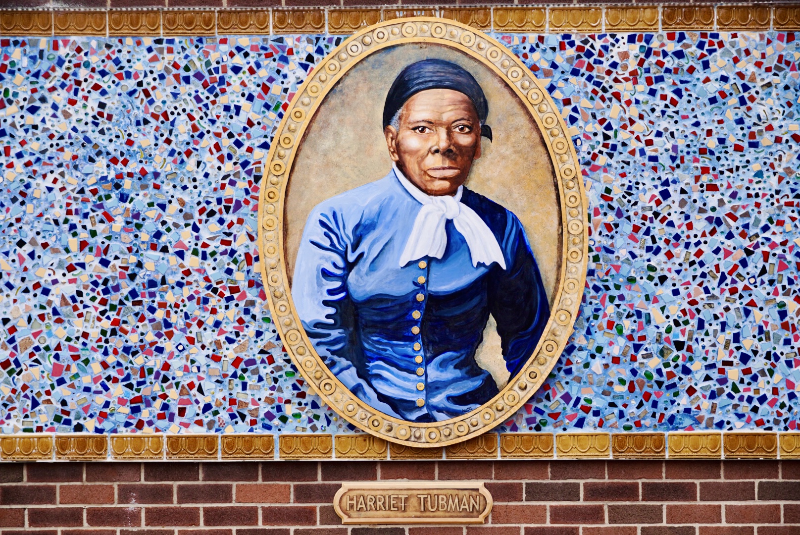 Mosaic in shades of blue  in the center is a  gold oval  with a picture of Harriet Tubman inside