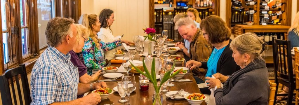 Hibercation Nine patrons sit at a restaurant table eating salads.