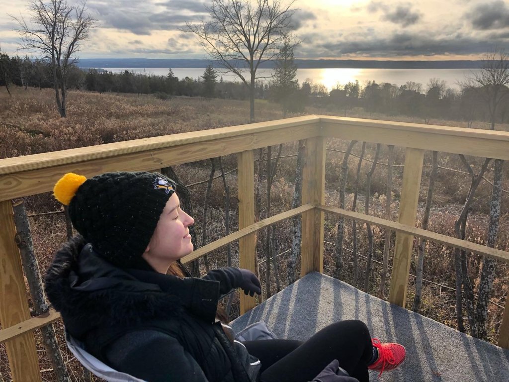 Plan Your Perfect Hibercation in Cayuga County -2024 One person sitting on a deck enjoying the outdoors in the winter