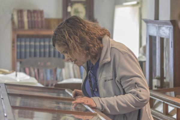 Celebrating 30 Years of Tourism Excellence in Cayuga County: Happy Birthday Tour Cayuga Woman looking at exhibit at Howland Stone Store Museum.
