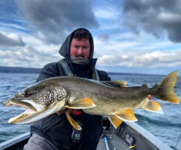 man on a boat holding a large trout