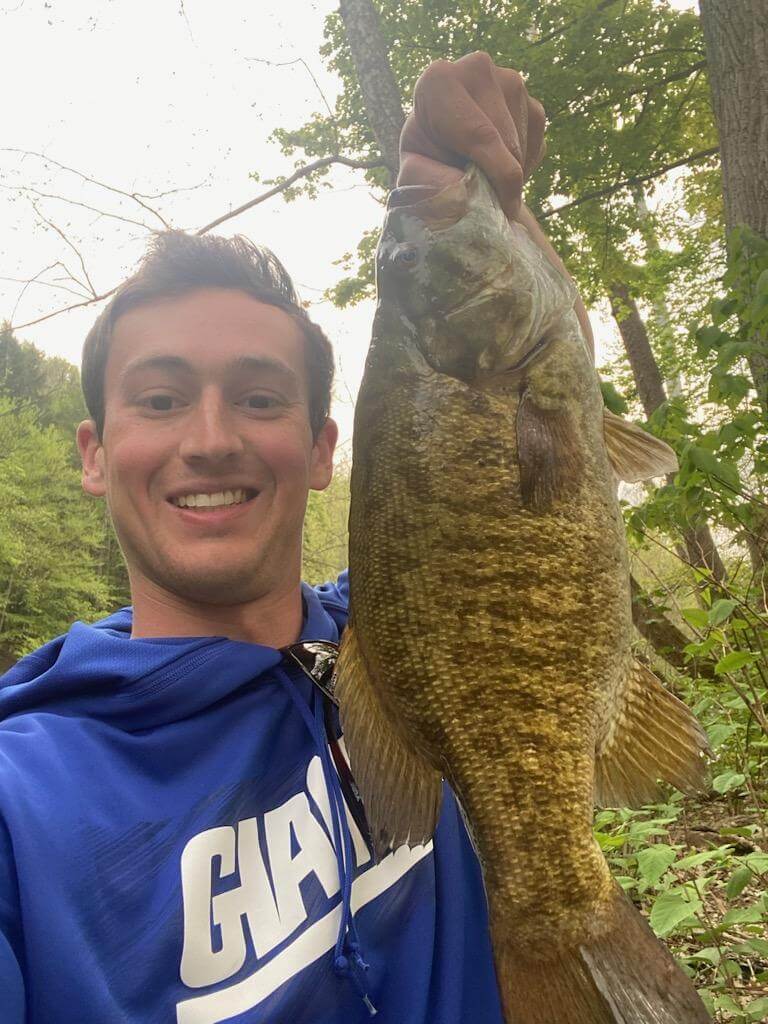 Go Deep for Summer Smallmouth Bass in Cayuga County Man on a boat holding a fish