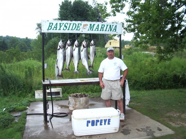 An Unforgettable Fishing Adventure with Popeye Charters owner of Popeye charters fishing in front of a line of freshly caught fish.