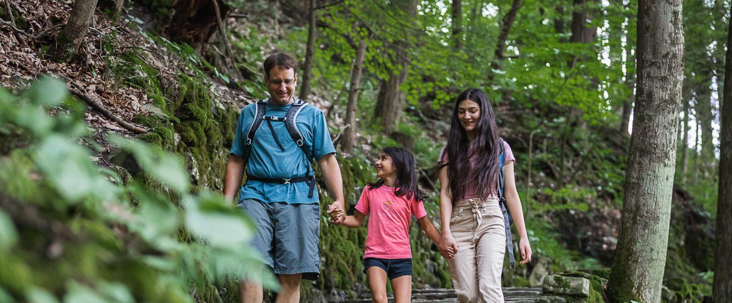 two adults and one child walking in a park in the summer